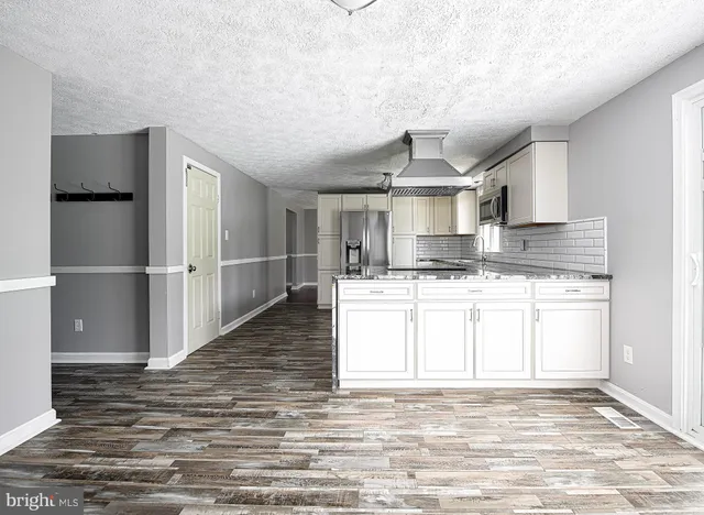 a large kitchen with kitchen island granite countertop a stove cabinets and wooden floor