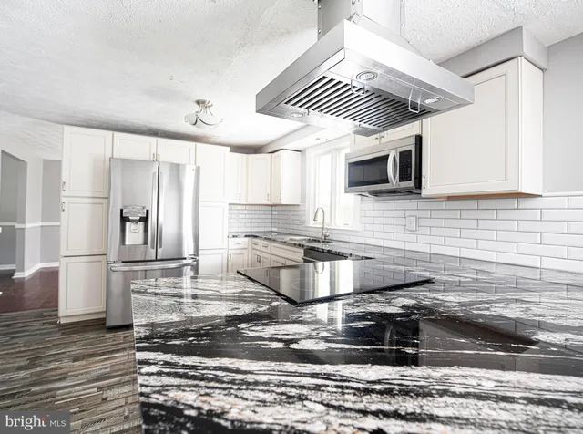 a kitchen with stainless steel appliances granite countertop a sink a stove and a microwave