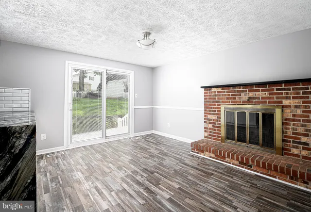 a view of a livingroom with wooden floor and a fireplace