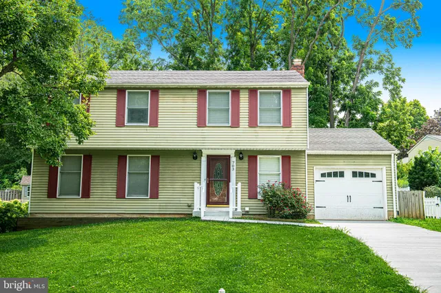 a house that has a big yard large trees with wooden fence