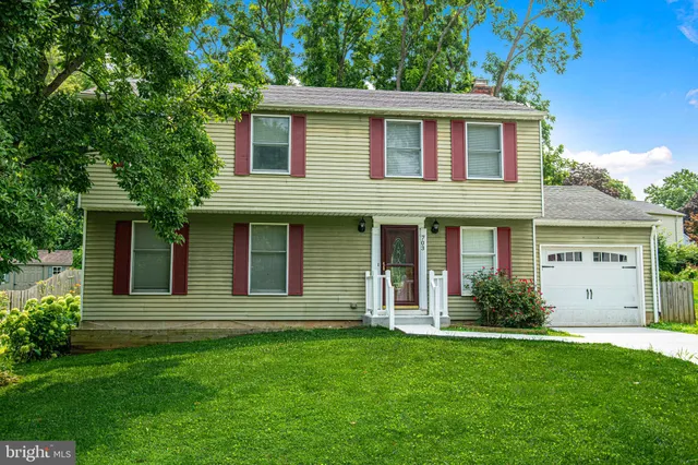 a view of a yard in front of a house with plants and large tree