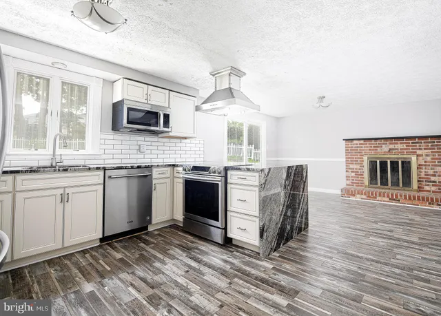 a kitchen with stainless steel appliances granite countertop a stove a sink and a microwave