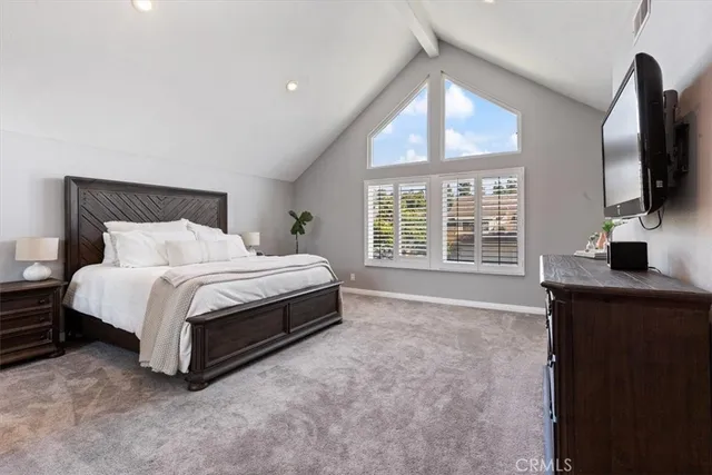a spacious bedroom with a bed and a flat tv screen on dresser