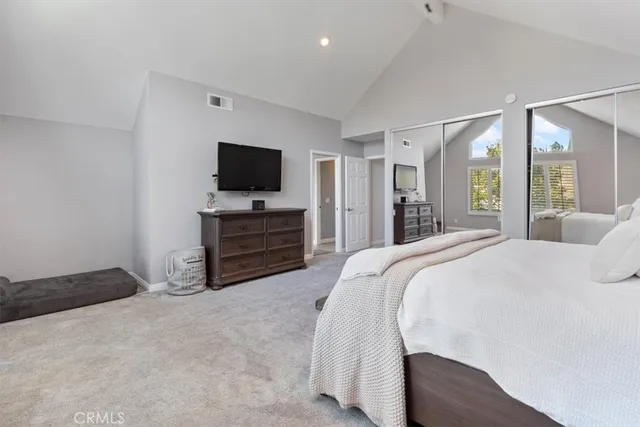 a spacious bedroom with a bed and a flat screen tv