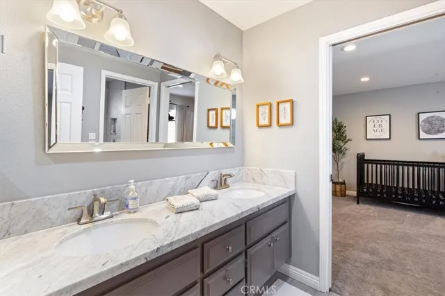 a en suite bathroom with a granite countertop double vanity sink a mirror and bathtub