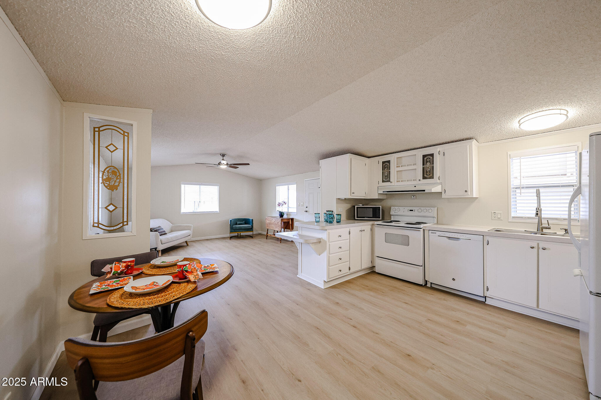 3901 East Pinnacle Peak Road, Unit 36 Phoenix, AZ 85050 - Photo 8 of 26 a large white kitchen with a stove a sink dishwasher and a refrigerator with wooden floor