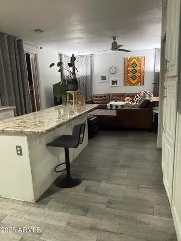 a living room with stainless steel appliances furniture a rug and a kitchen view