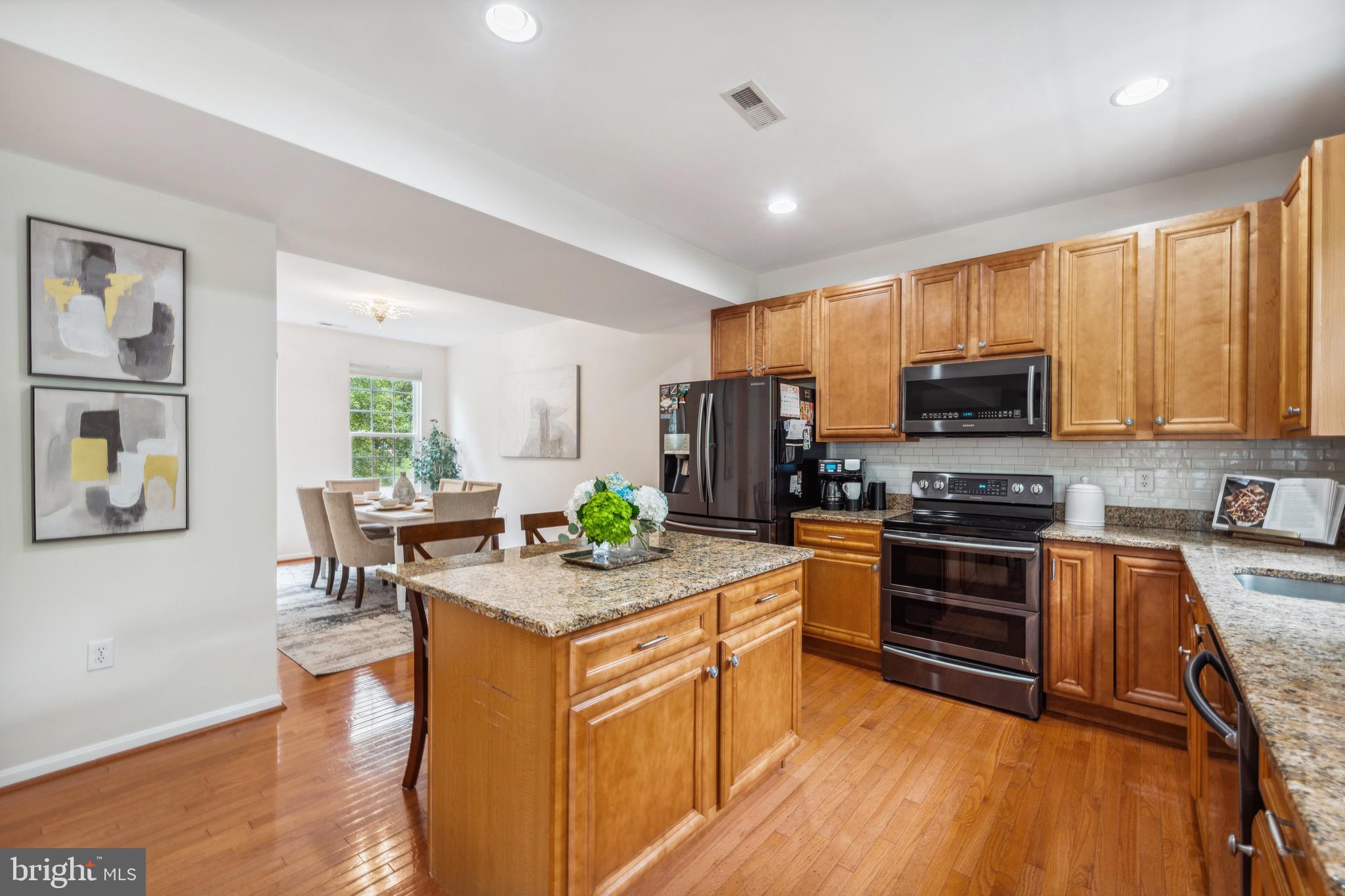 1407 James Way Edgewater, MD 21037 - Photo 12 of 30 a kitchen with granite countertop a stove top oven a sink dishwasher a dining table and chairs with wooden floor