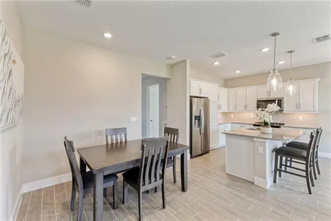 a kitchen with a dining table chairs stainless steel appliances and cabinets