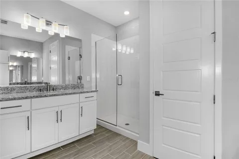 a bathroom with a granite countertop sink two mirror and shower