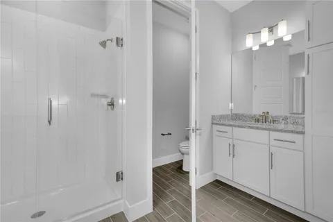 a bathroom with a granite countertop sink two mirror and shower