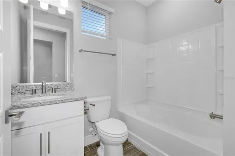 a bathroom with a granite countertop toilet a sink and a bathtub
