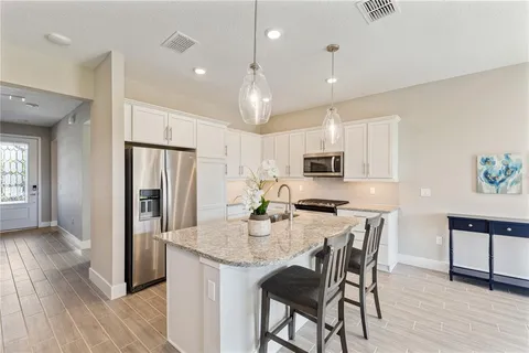 a kitchen with stainless steel appliances granite countertop a dining table chairs refrigerator and microwave
