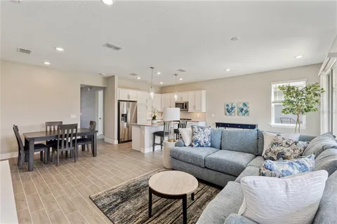 a living room with furniture and a dining table with wooden floor