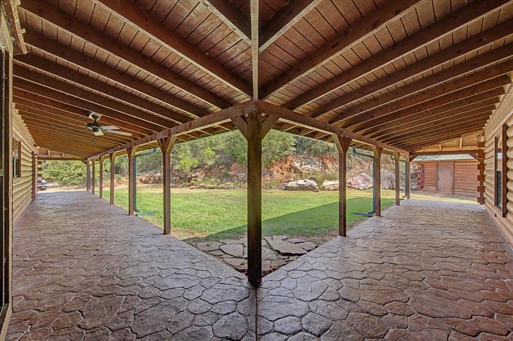 2789 Hanging Tree Road Bowie, TX 76230 - Photo 35 of 40 Covered patio with stamped concrete flooring, exposed wood beam ceiling, and a ceiling fan