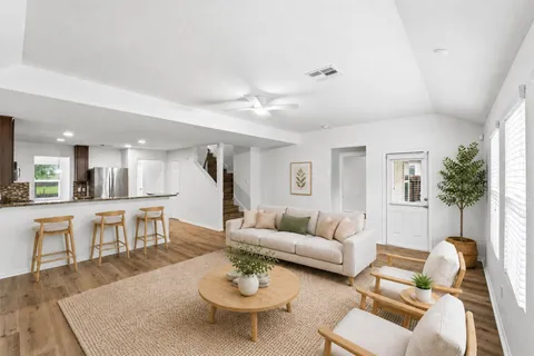 a living room with furniture kitchen view and a wooden floor