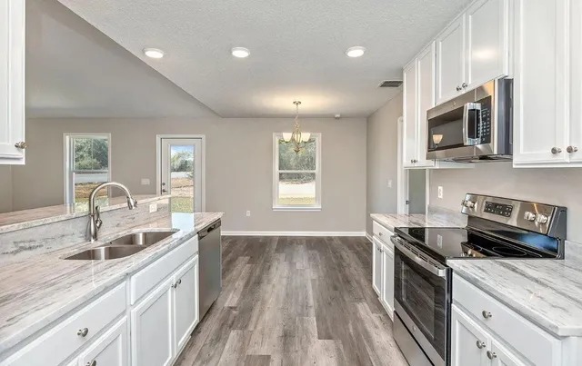 a kitchen with stainless steel appliances granite countertop a sink dishwasher stove and microwave
