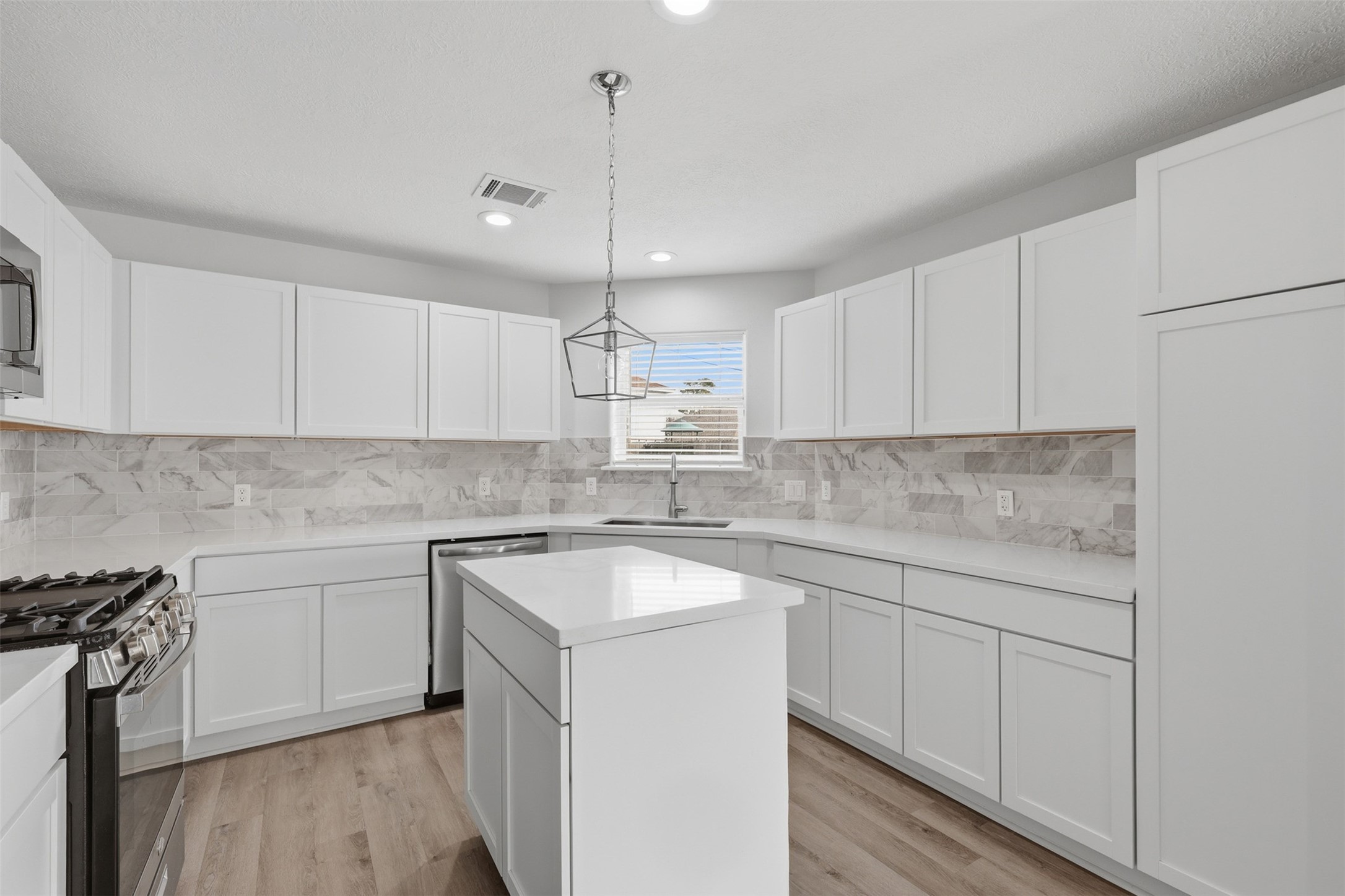 9026 McGallion Road Houston, TX 77022 - Photo 11 of 32 a kitchen with a sink a stove a refrigerator and white cabinets