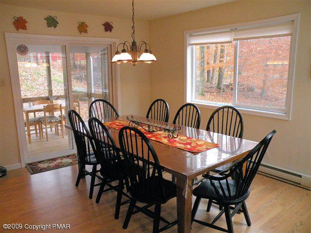 164 Elk Run Road Pocono Lake, PA 18347 - Photo 4 of 11 a dining room with furniture wooden floor a rug a potted plant and a chandelier