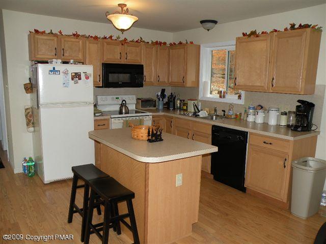 164 Elk Run Road Pocono Lake, PA 18347 - Photo 5 of 11 a kitchen with stainless steel appliances a sink a stove a refrigerator cabinets and a dining table
