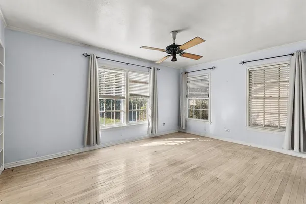 a view of an empty room with a window and wooden floor