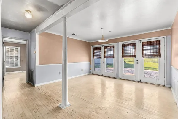 an empty room with wooden floor and windows