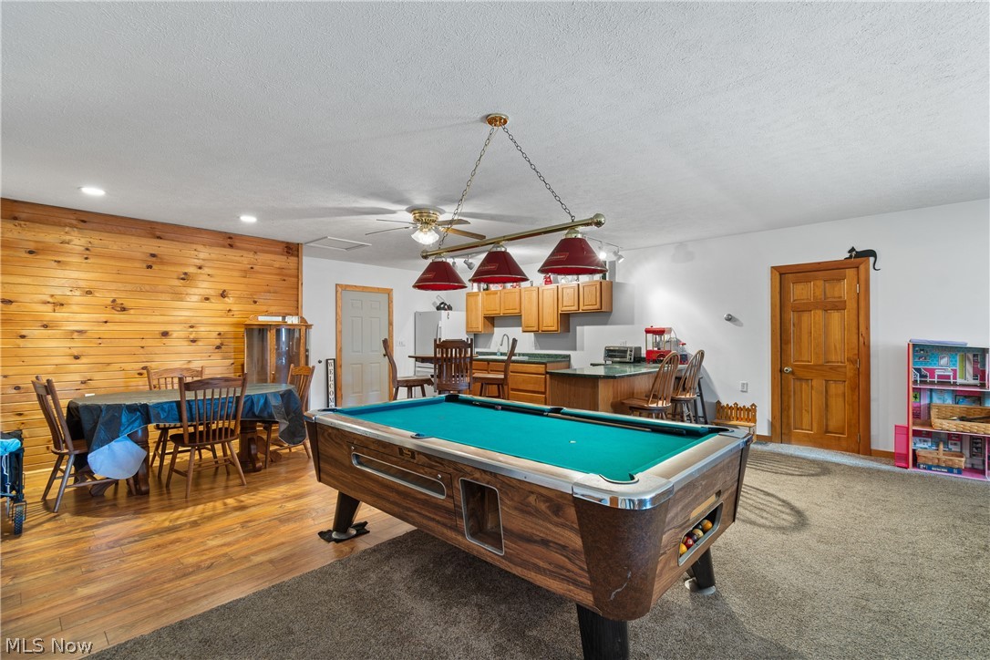 29395 Beitler Road Dennison, OH 44621 - Photo 29 of 33 Garage suite recreation room featuring pool table, wood walls, a ceiling fan, a textured ceiling, and wood finished floors