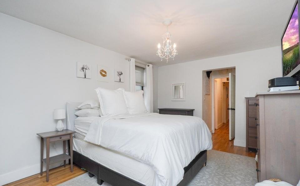 61 Oliver Street, Unit 2V Brooklyn, NY 11209 - Photo 18 of 23 a spacious bedroom with a bed and a chandelier