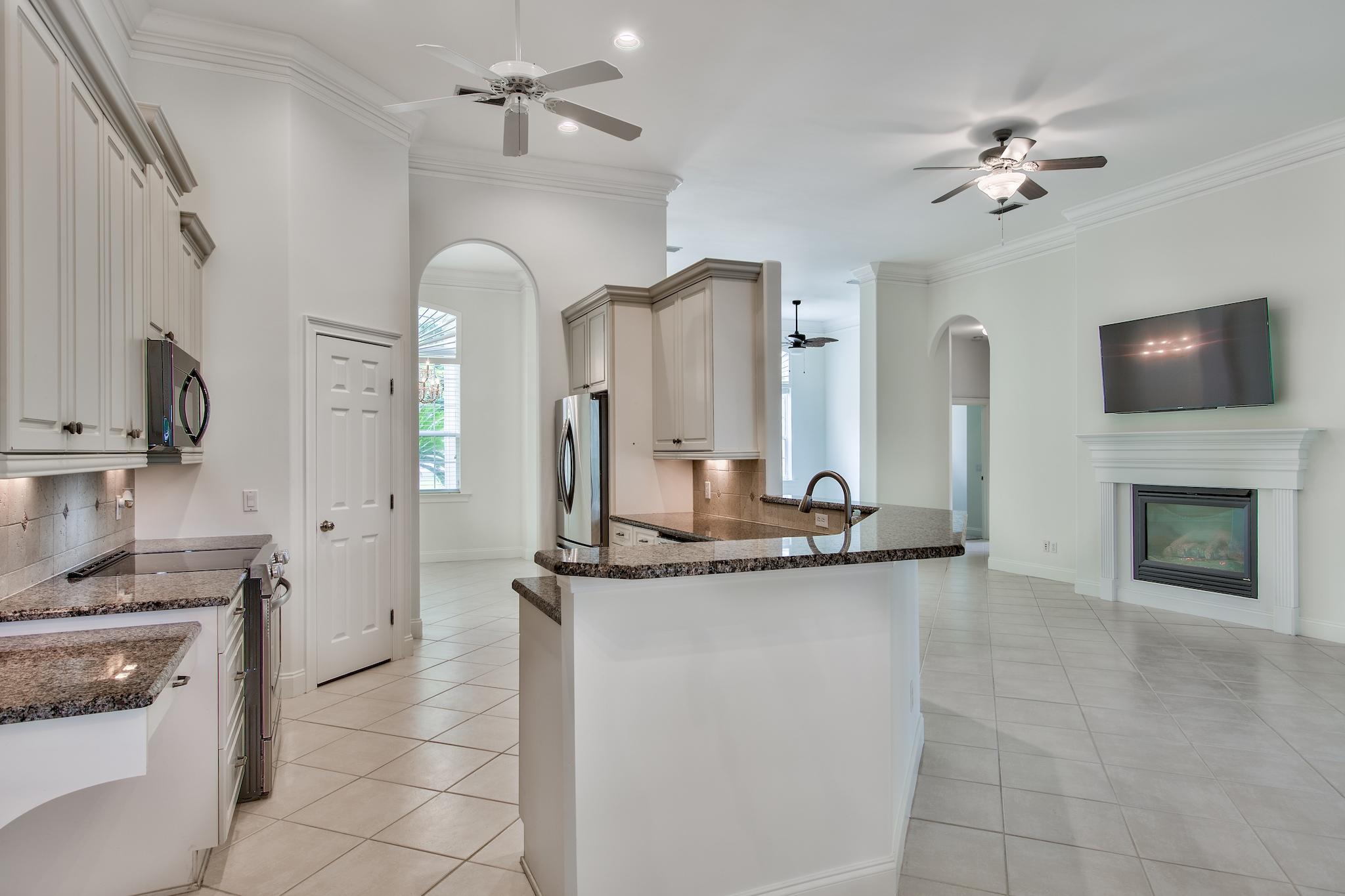 359 Indigo Loop Miramar Beach, FL 32550 - Photo 10 of 47 a kitchen with a sink a stove and a fireplace with wooden floor