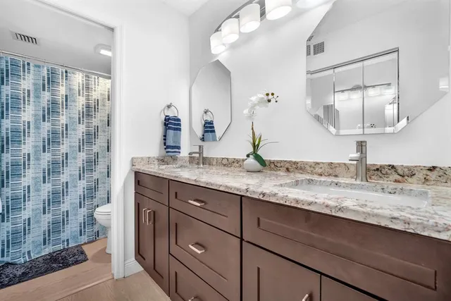 a bathroom with a granite countertop sink a mirror and shower