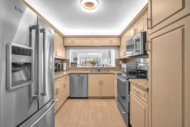 a kitchen with stainless steel appliances granite countertop a refrigerator a stove and a sink