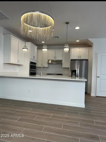 a view of kitchen with stainless steel appliances granite countertop a sink a stove and a wooden floors
