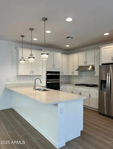 a large kitchen with granite countertop a large counter top stainless steel appliances and cabinets