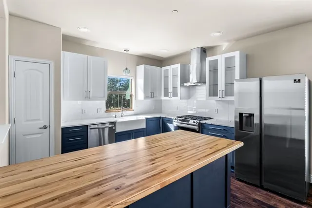 a kitchen with granite countertop a refrigerator stove sink and cabinets