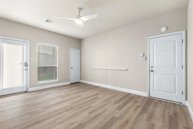 an empty room with wooden floor cabinet and windows