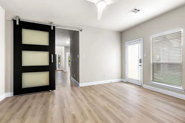 a view of an empty room with wooden floor and a window