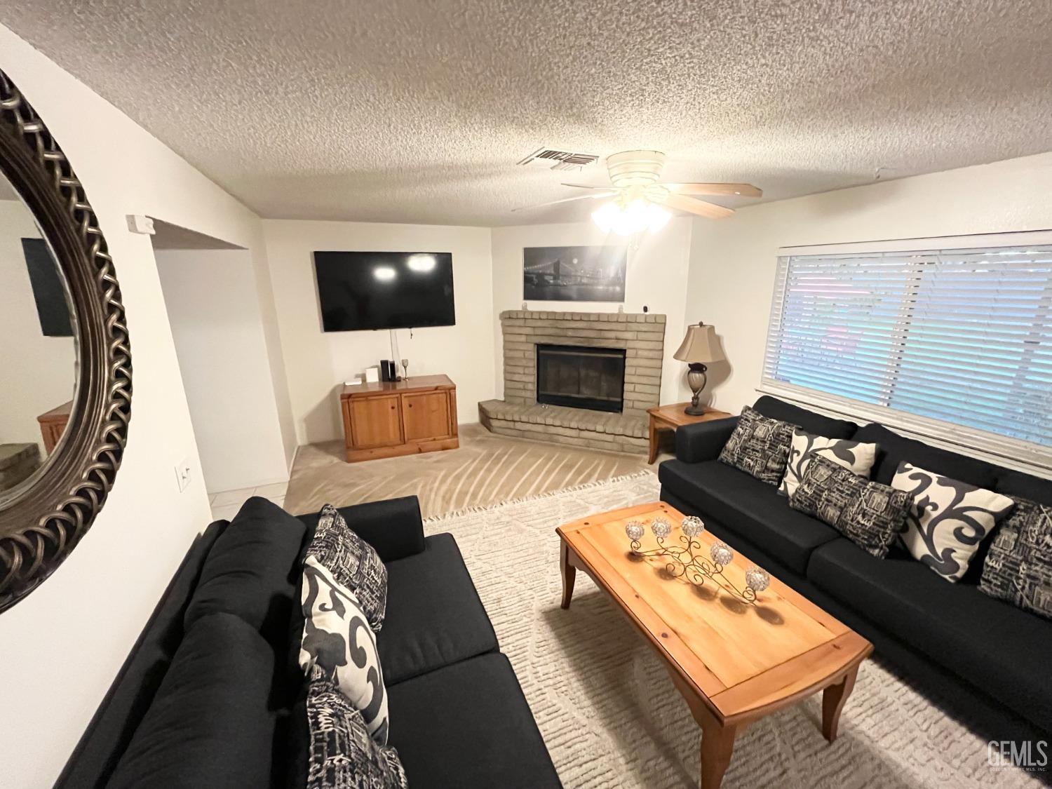 Undisclosed Address Bakersfield, CA 93304 - Photo 11 of 33 a living room with furniture a flat screen tv and a fireplace