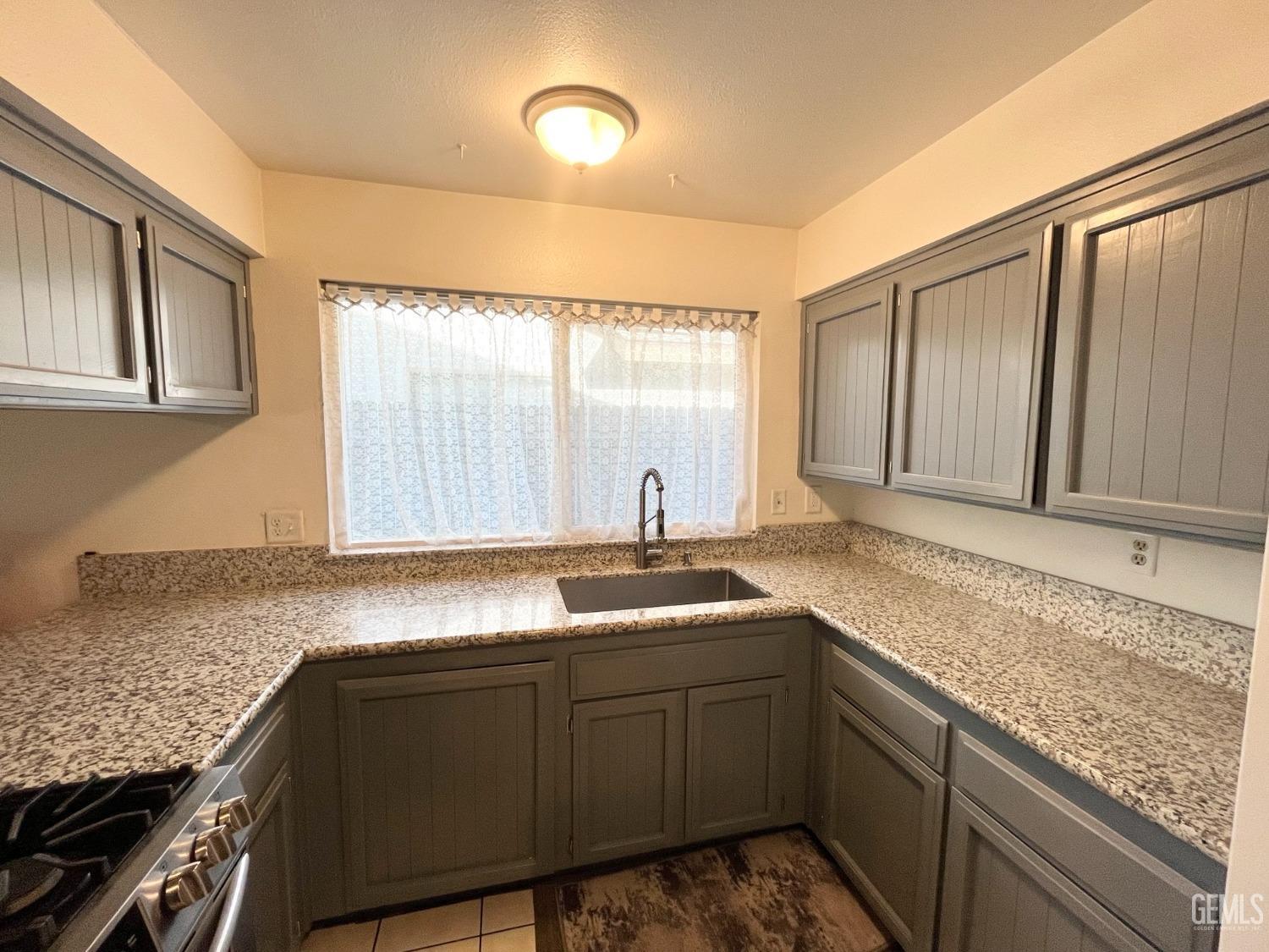 Undisclosed Address Bakersfield, CA 93304 - Photo 13 of 33 a kitchen with granite countertop sink cabinets and window