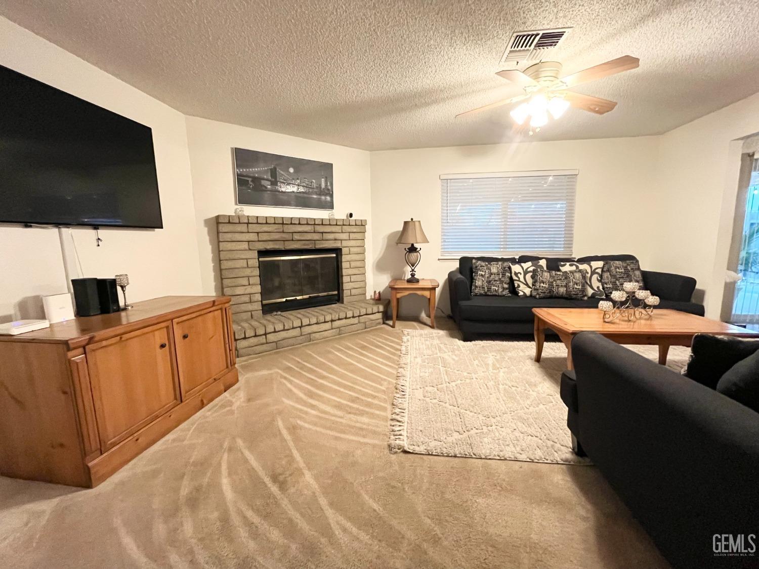 Undisclosed Address Bakersfield, CA 93304 - Photo 9 of 33 a living room with furniture a fireplace and a flat screen tv
