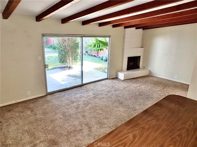 a view of an empty room with a fireplace and a window