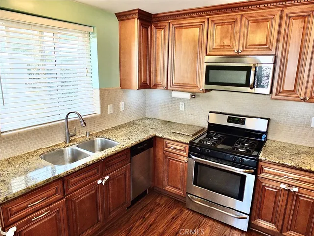 a kitchen with granite countertop a sink and steel appliances