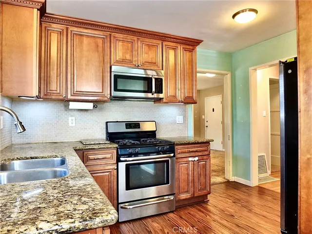 a kitchen with stainless steel appliances granite countertop a stove a sink and a microwave