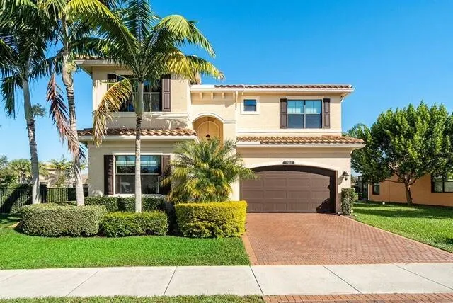 a front view of a house with a garden and a tree