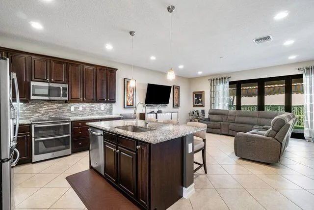 a kitchen with stainless steel appliances granite countertop a stove top oven a sink dishwasher a dining table and chairs with wooden floor