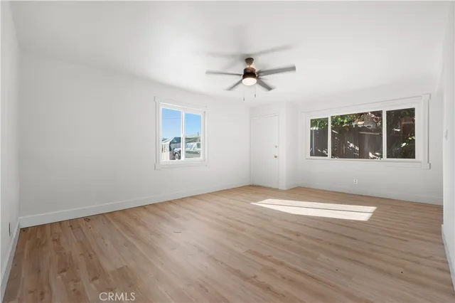 a view of empty room with wooden floor and fan