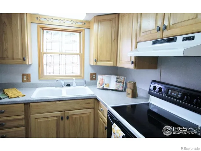 a kitchen with a sink a stove cabinets and a window