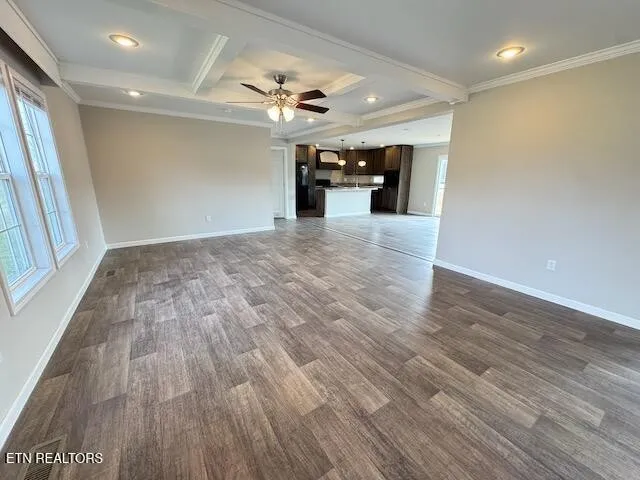 an empty room with wooden floor chandelier fan and windows