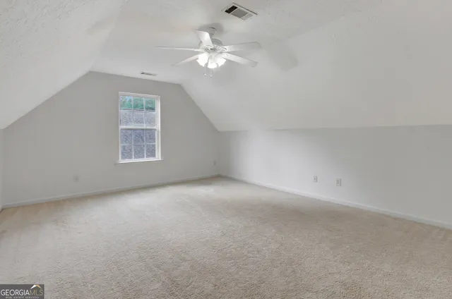 an empty room with a chandelier fan and windows