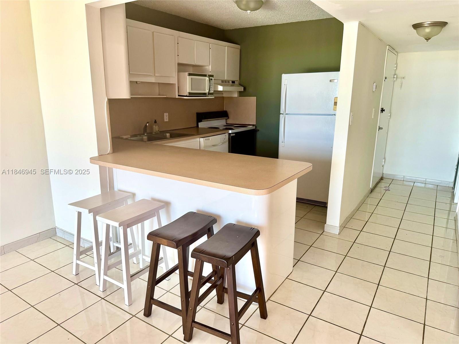 1228 West Avenue, Unit 1109 Miami Beach, FL 33139 - Photo 2 of 10 a kitchen with stainless steel appliances a refrigerator a stove a sink cabinets and a dining table
