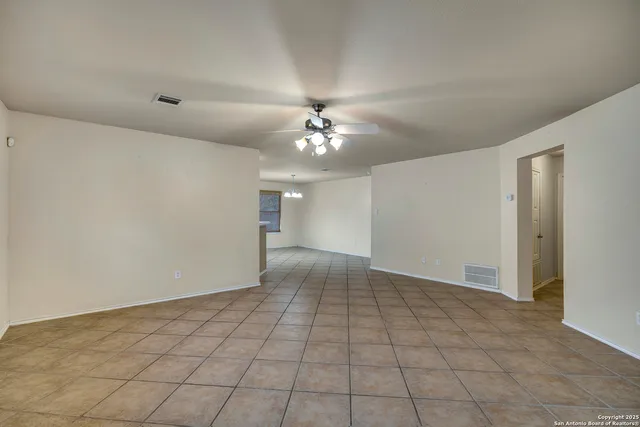 a view of an empty room with a chandelier fan